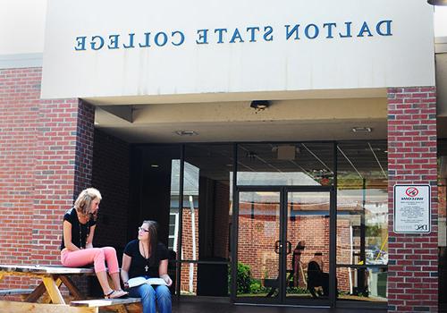 Students seated on picnic table in front of Dalton building